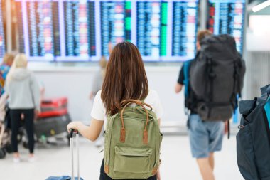 Young woman with backpack looking at the flight time information board in international airport, before check in. Travel, Vacation, trip and Transport concept