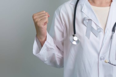 Beyin Kanseri Farkındalığı Mayıs ayında, gri renkli kurdeleli doktor, yaşam insanlarını desteklediği için. Sağlık ve Dünya Kanser Günü konsepti