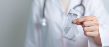 Beyin Kanseri Farkındalığı Mayıs ayında, gri renkli kurdeleli doktor, yaşam insanlarını desteklediği için. Sağlık ve Dünya Kanser Günü konsepti