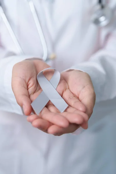 Brain Cancer Awareness May month, Doctor with grey color Ribbon for supporting life people. Healthcare and World cancer day concept