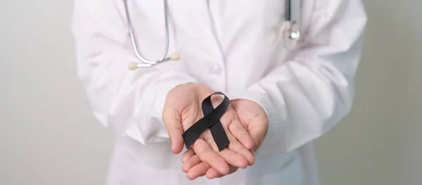Melanoma and skin cancer, Vaccine injury awareness month and rest in peace concepts. doctor holding black Ribbon