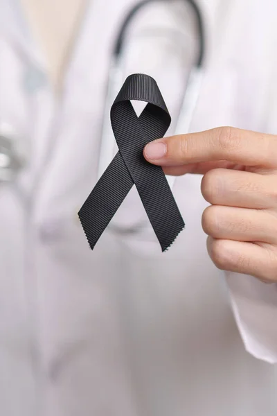 Melanoma and skin cancer, Vaccine injury awareness month and rest in peace concepts. doctor holding black Ribbon
