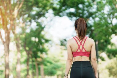 Pembe spor giysili genç bir kadın parkta kaslarını esnetiyor, sporcu kadın sabahları koşuya ve koşuya hazırlanıyor. Sağlık, fitness, egzersiz ve iş hayatı dengesi kavramları