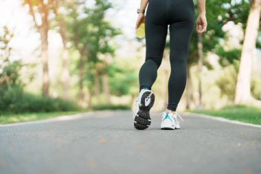 Sabah koşu yapan ve yolda yürüyen bir kadın, spor ayakkabılı genç bir kadın parkta koşuyor, atletin bacak kasları. Egzersiz, sağlık, sağlıklı yaşam tarzı ve egzersiz kavramları.