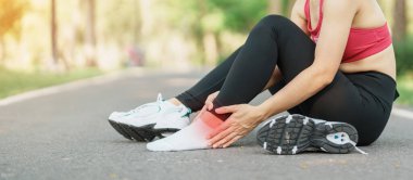 Koşarken kas ağrısı çeken genç bir kadın. Ayak bileği burkulması ya da aşil tendoniti yüzünden bacak ağrısı çeken bir koşucu kadın. Spor yaraları ve tıbbi konsept