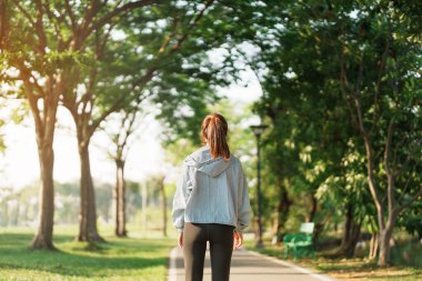 Pembe spor giysili genç bir kadın parkta kaslarını esnetiyor, sporcu kadın sabahları koşuya ve koşuya hazırlanıyor. Sağlık, fitness, egzersiz ve iş hayatı dengesi kavramları