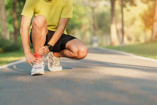 Young adult male with his muscle pain during running. runner man having leg ache due to Ankle Sprains or Achilles Tendonitis. Sports injuries and medical concept