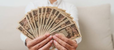 man hand holding Japanese Yen banknote stack. Thousand Yen money. Japan cash, Tax, Recession Economy, Inflation, Investment, finance and shopping payment concepts