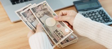 Woman hand counting Japanese Yen banknote with calculator. Thousand Yen money. Japan cash, Tax, Recession Economy, Inflation, Investment, finance, salary and payment concepts