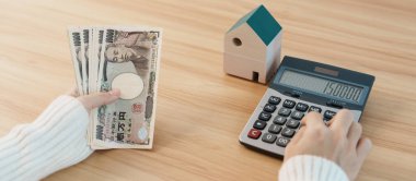 Woman counting Japanese Yen banknote with House model. Real Estate, Home, Mortgage, Japan cash, Tax, Recession Economy, Inflation, Investment, finance and savings concepts