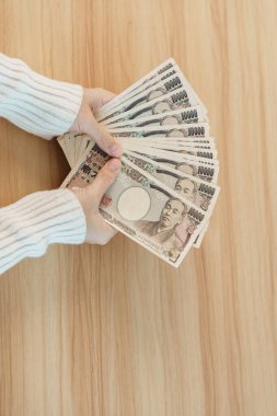 Woman hand counting Japanese Yen banknote over table background. Thousand Yen money. Japan cash, Tax, Recession Economy, Inflation, Investment, finance, savings, salary and payment concepts