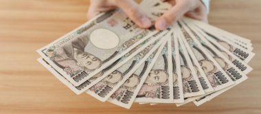 Woman hand counting Japanese Yen banknote over table background. Thousand Yen money. Japan cash, Tax, Recession Economy, Inflation, Investment, finance, savings, salary and payment concepts