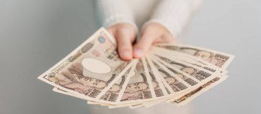 Woman hand holding Japanese Yen banknote stack. Thousand Yen money. Japan cash, Tax, Recession Economy, Inflation, Investment, finance and shopping payment concepts