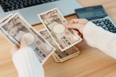 Woman hand counting Japanese Yen banknote with calculator. Thousand Yen money. Japan cash, Tax, Recession Economy, Inflation, Investment, finance, salary and payment concepts clipart