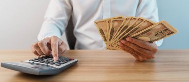 man hand counting Japanese Yen banknote with calculator. Thousand Yen money. Japan cash, Tax, Recession Economy, Inflation, Investment, finance, savings, salary and payment concepts