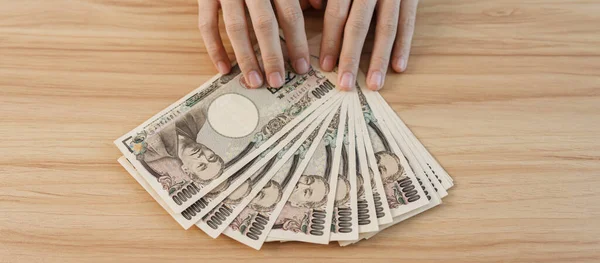 Woman hand counting Japanese Yen banknote over table background. Thousand Yen money. Japan cash, Tax, Recession Economy, Inflation, Investment, finance, savings, salary and payment concepts
