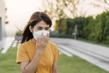 N95 solunum maskesi takan genç Asyalı kadın PM2.5 'u koruyor ve filtre ediyor veya şehirdeki kötü hava kirliliğine karşı partikül madde. Hava Kalite Endeksi, El Kaide, Sağlıksız, Sağlık Hizmetleri Konsepti