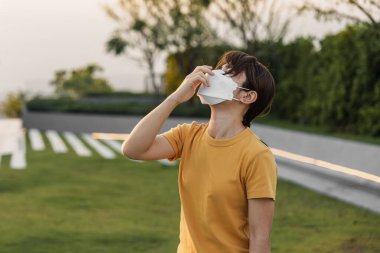 N95 solunum maskesi takan genç Asyalı kadın PM2.5 'u koruyor ve filtre ediyor veya şehirdeki kötü hava kirliliğine karşı partikül madde. Hava Kalite Endeksi, El Kaide, Sağlıksız, Sağlık Hizmetleri Konsepti