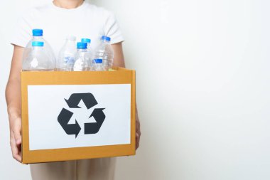 Gönüllü, plastik şişeyi evde ya da ofiste karton kutuya koyuyor. Geri Dönüşüm çöpünü elle ayırmak. Ekoloji, Çevre, Kirlilik, Geri dönüşüm, Atık Yönetimi ve Çöp Ayrıştırma Konsepti