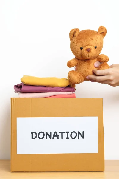 子供の寄付 ボランティア 寄付と配達の概念 支援と貧困層 ホームレスの人々を助けるために自宅の寄付箱にベア人形と服を手に持っています テキストのコピースペース — ストック写真