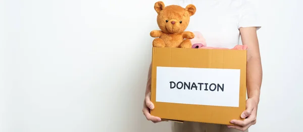 子供の寄付 ボランティア 寄付と配達の概念 支援と貧困層 ホームレスの人々を助けるために自宅の寄付箱にベア人形と服を手に持っています テキストのコピースペース — ストック写真