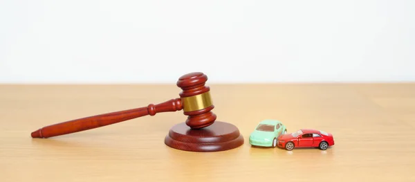 Car Law, Insurance, auto Tax, Auction and Bidding concepts. crashed small toy car models with Judges gavel on desk in courthouse.