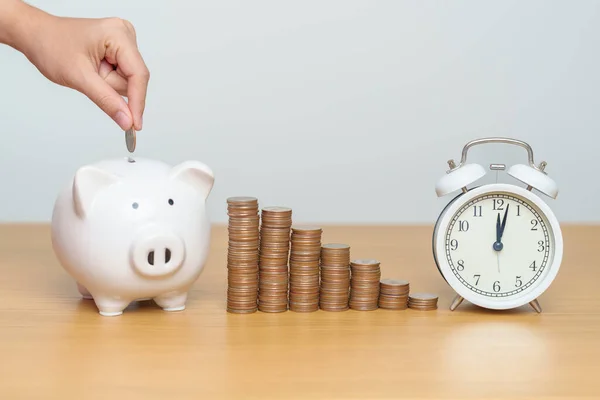 Money Saving for Future Plan, Retirement fund, Pension, Investment, Wealth Business and Financial concepts. hand putting coin into piggy bank with clock, Counting and stack arrangement for deposit