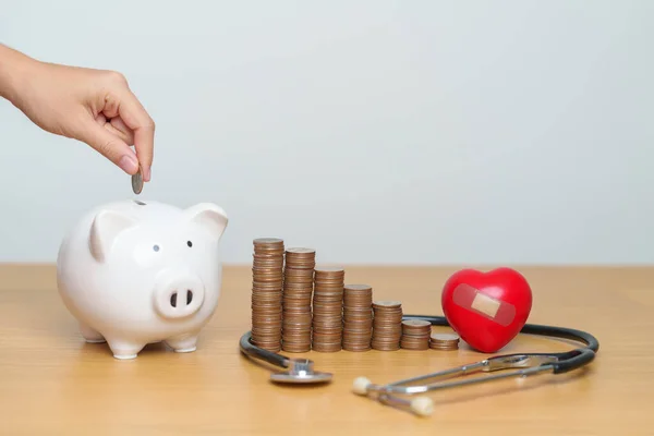 Money Saving, Health Insurance, Medical, Donation and Financial concepts. hand putting coin into piggy bank with stethoscope and Heart, Money stack Counting arrangement for deposit and Healthcare cost