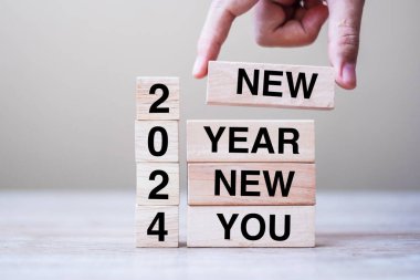 Yeni Yıl 2024 yazısıyla ahşap blokla el ele tutuşmak masa arkasında yeni bir sen. Çözüm, strateji, hedef, iş ve tatil kavramları
