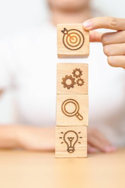 Kadın dart tahtasını dişlinin üstünde tutuyor, büyütüyor ve ampul simgesi engelliyor. iş planlama süreci, hedef, hedef, hedef, görev, eylem, araştırma, takım çalışması ve fikir kavramı