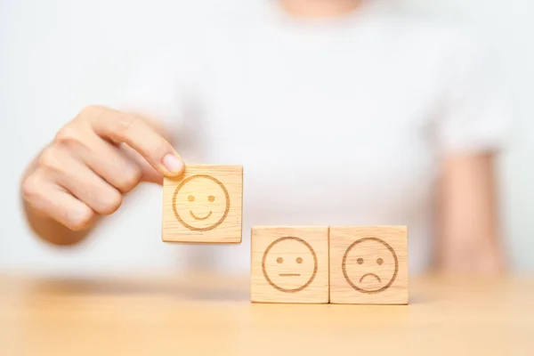 stock image Hand choosing smile face from Emotion block for customer review, good experience, positive feedback, satisfaction, survey, evaluation, assessment, mood and world mental health day concept