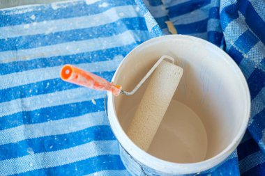 Duvarı boyarken kova ile boya fırçası. Ev ya da dairenin yenilenmesi, bakımı ve geliştirilmesi