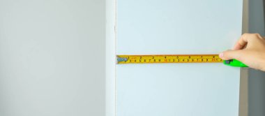 Evdeki mobilyaları ölçmek için mezura kullanan bir adam. DIY, İç mimari, onarım ve geliştirme ev veya apartman kavramları