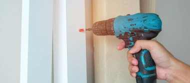 Evde mobilya montajı yapan kablosuz tornavida kullanan bir adam, işte elektrikli tornavida kullanan bir marangoz.