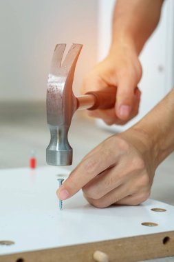 Çekiç kullanan bir adam tahta tahtalara çivi çakıyor, evde mobilya monte ediyor ya da tamir ediyor. DIY, yenileme, onarım ve geliştirme konseptleri