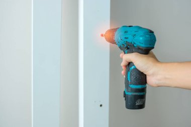 Evde mobilya montajı yapan kablosuz tornavida kullanan bir adam, işte elektrikli tornavida kullanan bir marangoz.