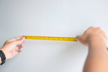 Evdeki duvar arkasını ölçmek için mezura kullanan bir adam. DIY, İç mimari, onarım ve geliştirme ev veya apartman kavramları