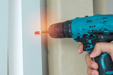 Evde mobilya montajı yapan kablosuz tornavida kullanan bir adam, işte elektrikli tornavida kullanan bir marangoz.