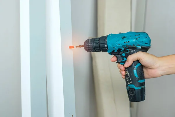 stock image man using a cordless screwdriver assembling furniture at home, Carpenter working with electric screwdriver on the work