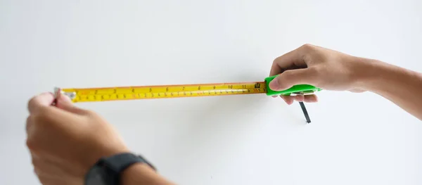 stock image Man hand using tape measure for measuring with wall backgrounds at home. DIY, Interior design, repairing and improvement home or apartment concepts