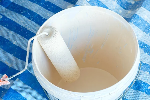 Stock image paint roller brush with bucket during painting the wall. Renovation, maintenance and development of home or apartment