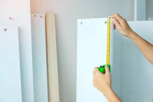 Stock image Man hand using tape measure for measuring furniture at home. DIY, Interior design, repairing and improvement home or apartment concepts