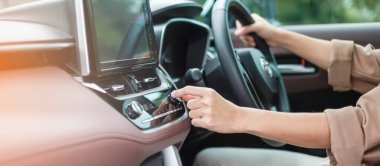 Woman hand adjusting temperature the air flowing during driving car on the road, air conditioner cooling system inside the car. Adjust, temperature and transport concept