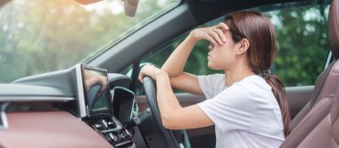 Araba kullanırken gergin ve sinirli bir kadın. Asyalı kız trafik sıkışıklığında araba kullandıktan sonra baş ağrısı yüzünden yorgun ve yorgun. Uykulu, esnetici ve sarhoş konsepti