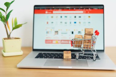 Dizüstü bilgisayarında alışveriş arabası olan kutular. Çevrimiçi alışveriş, Pazar yeri platformu web sitesi, teknoloji, ekommerce, nakliye teslimatı, lojistik ve çevrimiçi ödeme kavramları