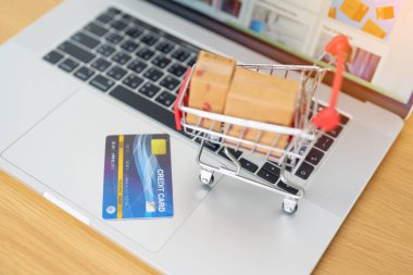 Dizüstü bilgisayarında kredi kartı olan kutular. Çevrimiçi alışveriş, Pazar yeri platformu web sitesi, teknoloji, ekommerce, nakliye teslimatı, lojistik ve çevrimiçi ödeme kavramları