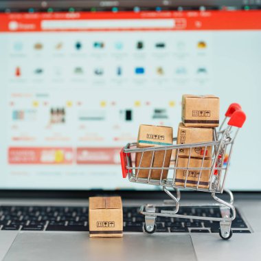 Dizüstü bilgisayarında alışveriş arabası olan kutular. Çevrimiçi alışveriş, Pazar yeri platformu web sitesi, teknoloji, ekommerce, nakliye teslimatı, lojistik ve çevrimiçi ödeme kavramları