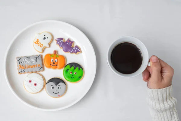 Kobieta Trzyma Filiżankę Kawy Podczas Jedzenia Śmieszne Ciasteczka Halloween Szczęśliwego — Zdjęcie stockowe