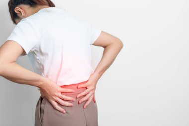 Gri arka planda kas ağrısı olan yetişkin bir kadın. Piriforis Sendromu, bel ağrısı ve omurga baskısı nedeniyle sırt ağrısı çeken yaşlı bir kadın. Ofis sendromu ve tıbbi konsept
