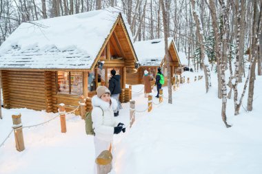 Furano 'yu ziyaret eden kadın turist, kazaklı gezgin kışın Snow' la Ningle Terrace Cottages 'ı gezen gezgin. Japonya 'nın Hokkaido şehrinde önemli ve popüler bir yer. Seyahat ve Tatil kavramı